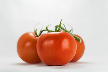 Close-up of a bunch of three tomatoes on white background