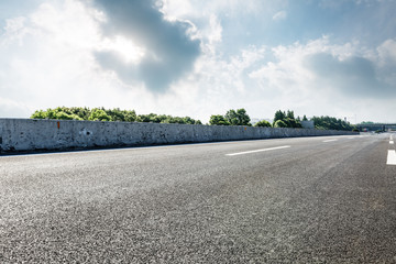 asphalt road and green forest under the blue sky