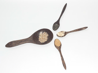 Grains in a wooden spoon on a white background.