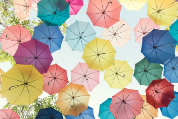 Fototapeta na wymiar Lots of colorful umbrellas flying in sky over city street during summer festival. Fun and happy background concept. Vintage and retro threme.