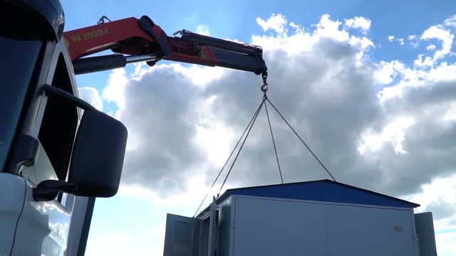The construction crane on the machine raises the transformer electric box