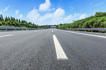 asphalt road and green forest under the blue sky