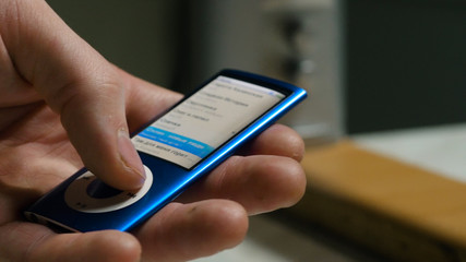 Music player in male hand, on home interior background. Toggles the music on the player close up © Media Whale Stock