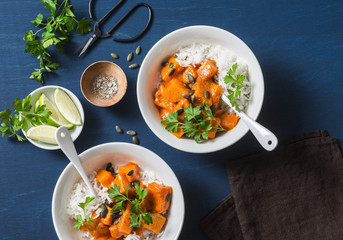 Pumpkin coconut milk curry sauce with rice on a blue background, top view. Indian food. Vegetarian food concept - obrazy, fototapety, plakaty