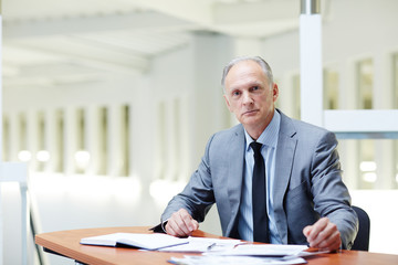 Obraz premium Senior boss in formalwear sitting by workplace in office