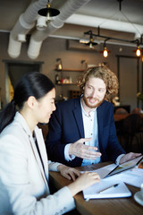 Start-up meeting of two young confident employees in cafe