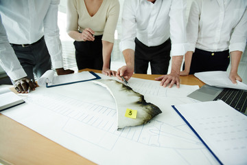 Close-up shot of multi-ethnic aircraft accident board studying plane wreckage while having working...
