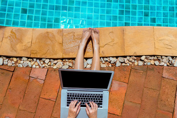 Woman bikini using laptop computer blank screen at swimming pool in resort edge, Top view