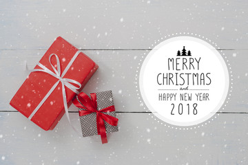 Christmas and New Year holidays gift box on white wooden table with falling snow effect.Flat lay with Merry Christmas & Happy New Year 2018 sign.Gifts and congratulations concept..