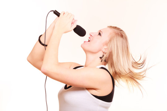 Blonde woman singing to microphone, profile view
