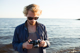 Young photographer with photocamera making photos of natural views by seaside