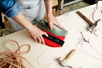 Master of own cobbler workshop doing his work by large table