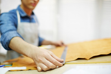 Shoemaker measuring piece of beige suede or leather for new order