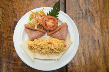 Table with nicely served American breakfast - sausages, vegetables, omelette, egg dishes. top view Selective focus.