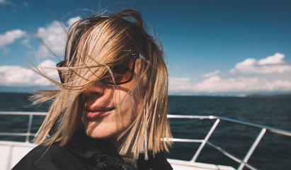Woman on boat deck in windy weather, wind blow her hair.