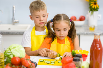 Children cut cucumbers for vegetable salad