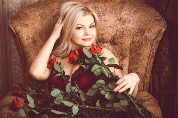 Fototapeta premium Middle age blonde hair woman Sitting in armchair wear in Marsala Lace Lingerie. Mature caucasian woman in vintage romantic style dressed in lingerie poses in a bedroom