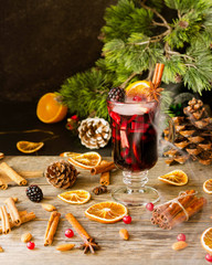Obraz na płótnie Canvas glass of hot mulled wine for the new year with ingredients for cooking, nuts and Christmas decorations