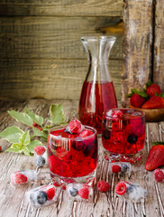 Summer berry lemonade with frozen berries on a wooden rustic table, selective focus