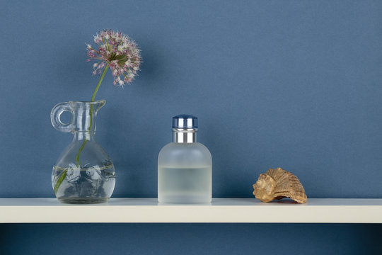 Perfume And Vase With A Flower On White  Shelf On Blue Wallpaper