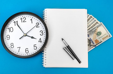 Blank notepad with money and clock. Business concept. Top view.