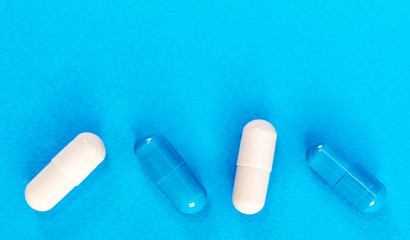 Row of medical capsules on a blue background. Top view. Medical background.