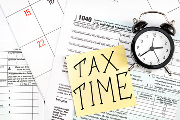 Sticker with words "Tax time" and clock on the tax form. Business concept.