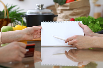 Close-up of human hands pointing into note book copy space area in the kitchen.  So much ideas for tasty cooking. Vegetarian, healthy meal and friendship concept