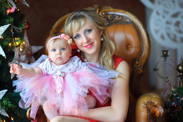 happy mother with baby sitting near a festive Christmas tree, Christmas morning