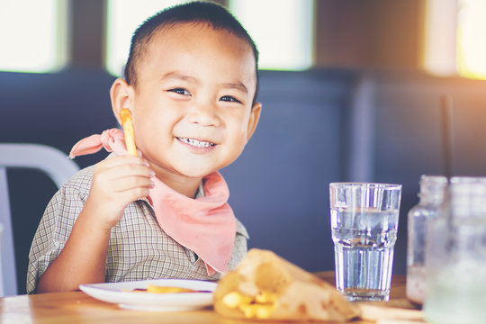 little boy enjoy eating french fries with his hands