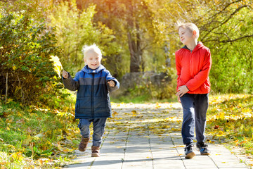 Two smiling boys run through the autumn park