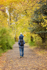 Obraz premium Father and son on their shoulders walk through the autumn park. Back view