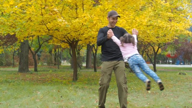 Circling the child. Father circling a happy daughter in an autumn park.