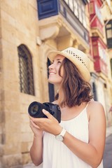 Young woman photographer with camera sightseeing in Valletta, Malta