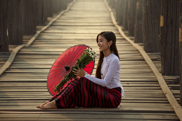 Myanmar Beautiful woman in U Bein Bridge morning time happiness with withe flower and red umbrella...