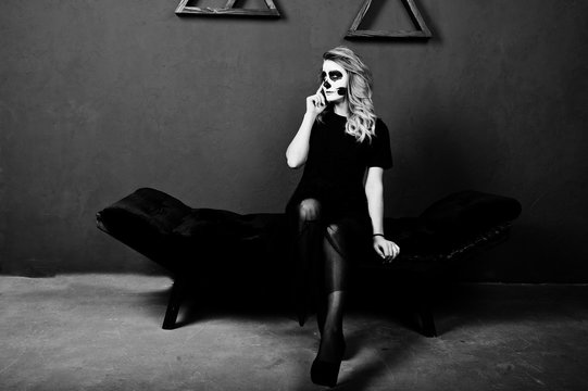 Halloween skull make up girl wear in black against blue wall at studio.
