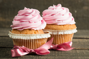 Closeup of cupcakes with vanilla, berries, pink and white cream, chocolate and sprinkles on wooden background. Selective focus. Sweet dessert tasty food concept muffin.