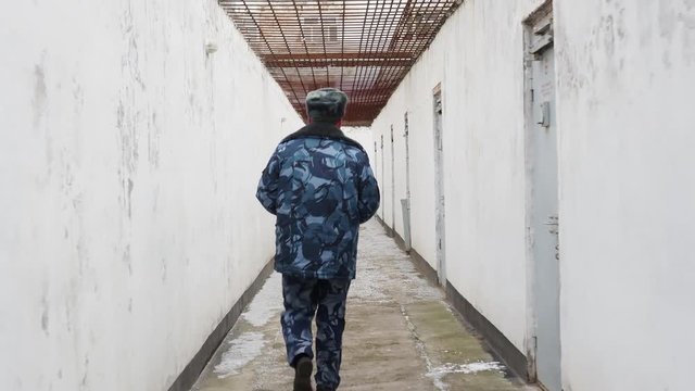 Prison officer walking in inter yard in russian penitentiary colony, jail, prison at winter glidecam