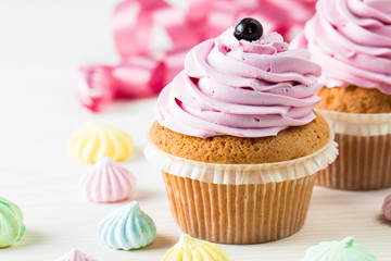 Closeup of cupcakes with vanilla, berries, pink and white cream, chocolate and sprinkles on wooden background. Selective focus. Sweet dessert tasty food concept muffin.