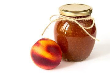 Nectarine jam in a glass jar and fresh peaches on white background