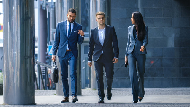 Male and Female Business People Walk and Discuss Business. They're all Working in Central Business District.