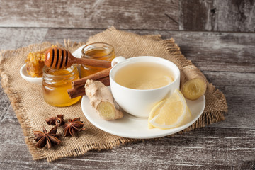 A glass cup of green natural tea with ginger, lemon, mint and honey on wooden rustic background. Healthy drink.