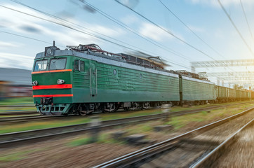 Obraz premium Locomotive electric with a freight train at high speed rides by rail.