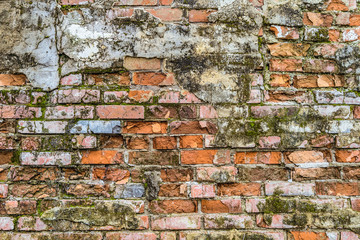 Vintage mossy brick wall texture. Background of an old weathered, thawed and cracked red brick wall.