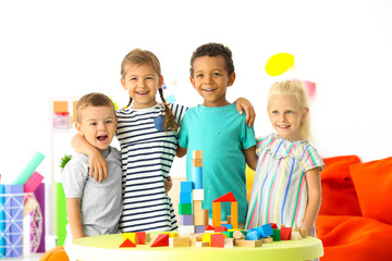 Cute children playing with blocks on table indoor