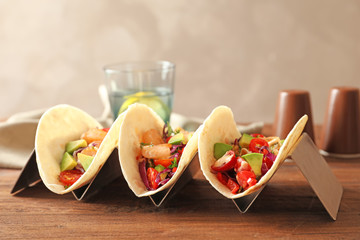 Holder with delicious shrimp tacos on wooden table