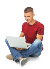 Handsome young man sitting and using laptop against white background