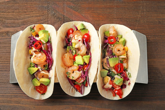 Holder with delicious shrimp tacos on wooden table