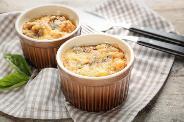 Ramekins with delicious sausage casserole on table