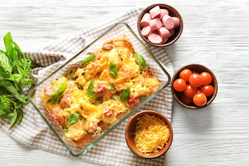 Composition with delicious sausage casserole in baking dish on table